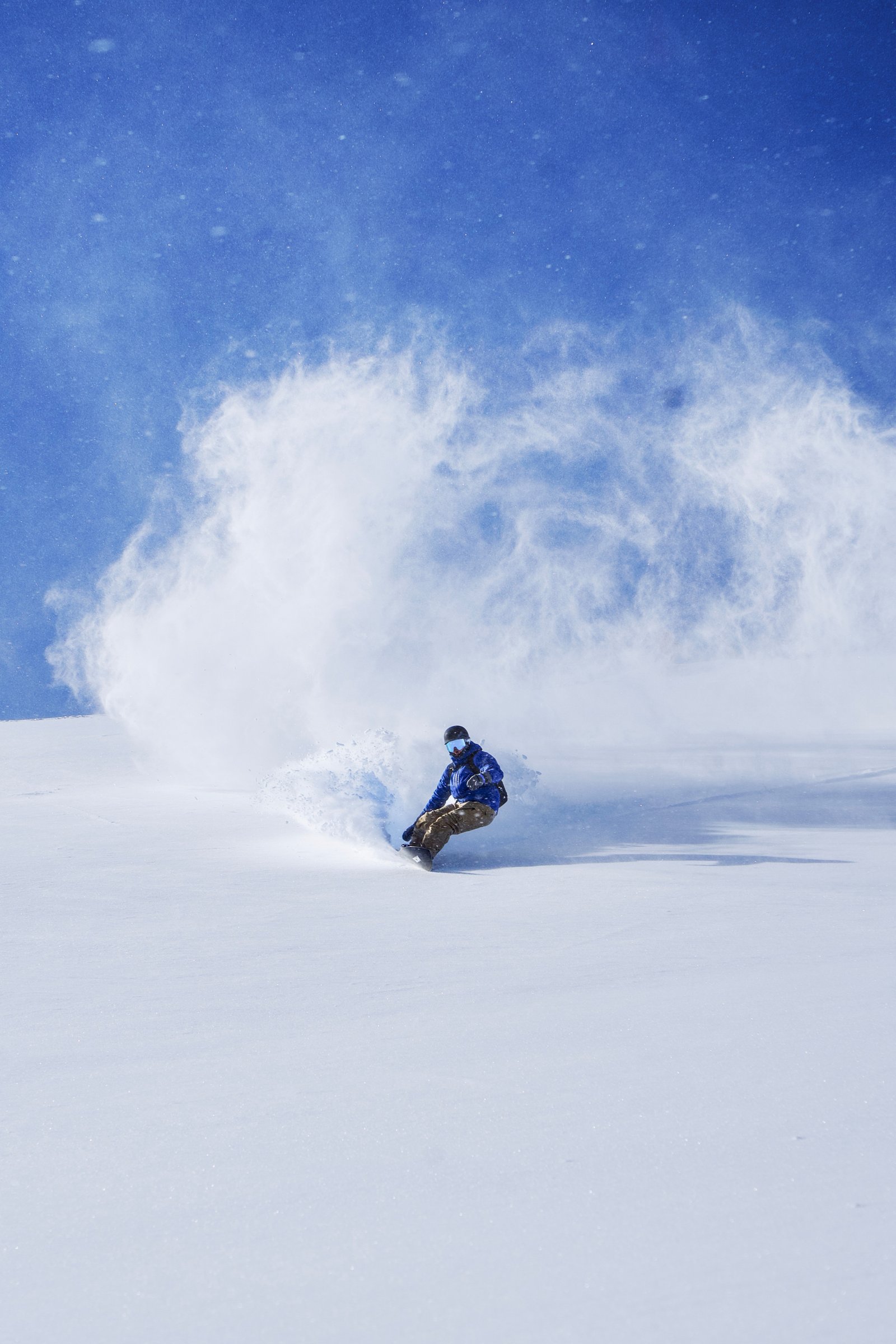 Skier throwing powder spray on a steep winter run.